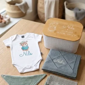 Babybox Premium mit Kurzarm-Body und blauem Herzi-Bärli-Motiv, einer Babydecke, Spucktüchern, Waschlappen und Lätzchen. Personalisiert mit dem Namen "Nils". | werktraum33
