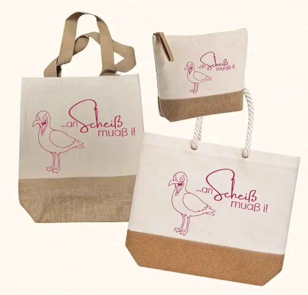 Premium-Taschen-Kollektion von werktraum33 mit kackender Möwe und Spruch „an Scheiß muaß i“, bestehend aus Shopper, Strandtasche und Kulturtasche aus Canvas und Jute.