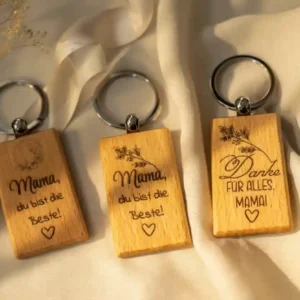 Drei personalisierte rechteckige Holz-Schlüsselanhänger mit Gravur für Mama, verschiedene Symbole und Sprüche auf warmem Leinenhintergrund. | werktraum33