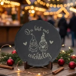 Schieferplatte rund mit Lasergravur: zwei Wichtel mit Herzen und der Spruch „Du bist mir wichtelig“ auf einem Holzständer von werktraum33.